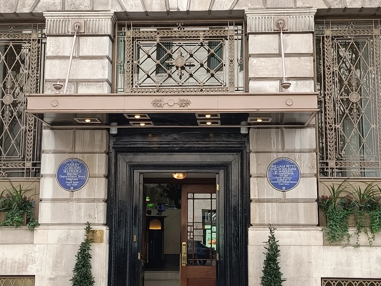 Entrance to a historic building with decorative black and gold door frame and blue plaques.