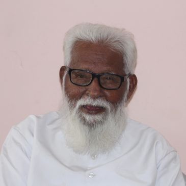 Elderly man with white beard and glasses smiling.