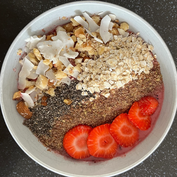 A nutritious bowl with strawberries, chia seeds, oats, nuts, and coconut flakes.