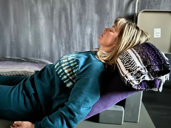A woman relaxing with eyes closed, leaning on a towel-covered support.