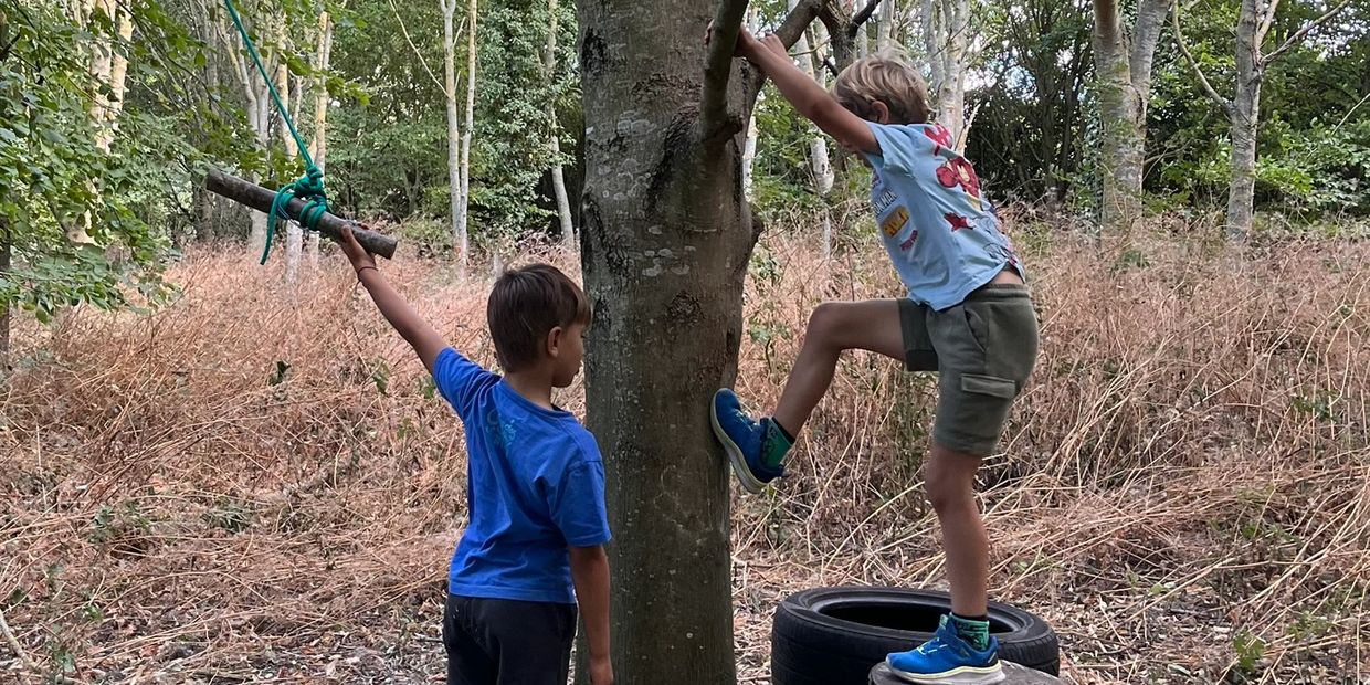 Two boys playing outdoors with a rope and tires.