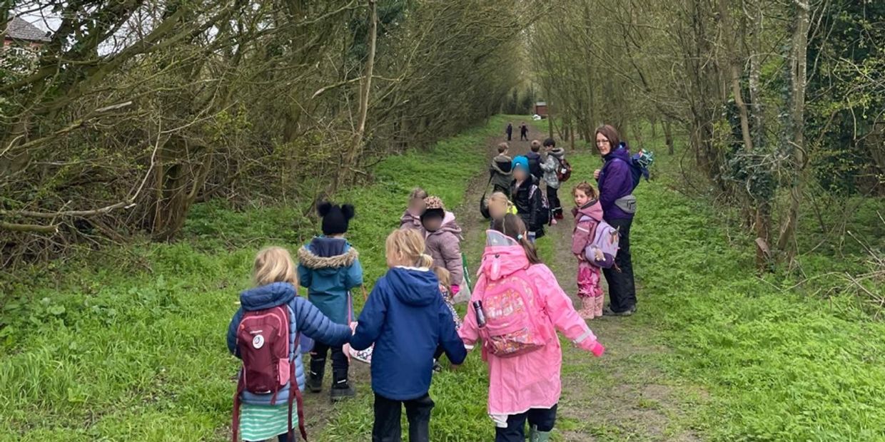 Children walking hand in hand on a grassy path during an outdoor activity.