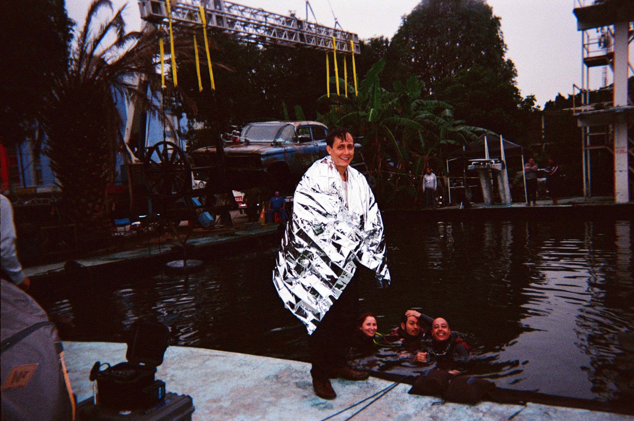 Persona envuelta en manta térmica junto a otras en el agua.