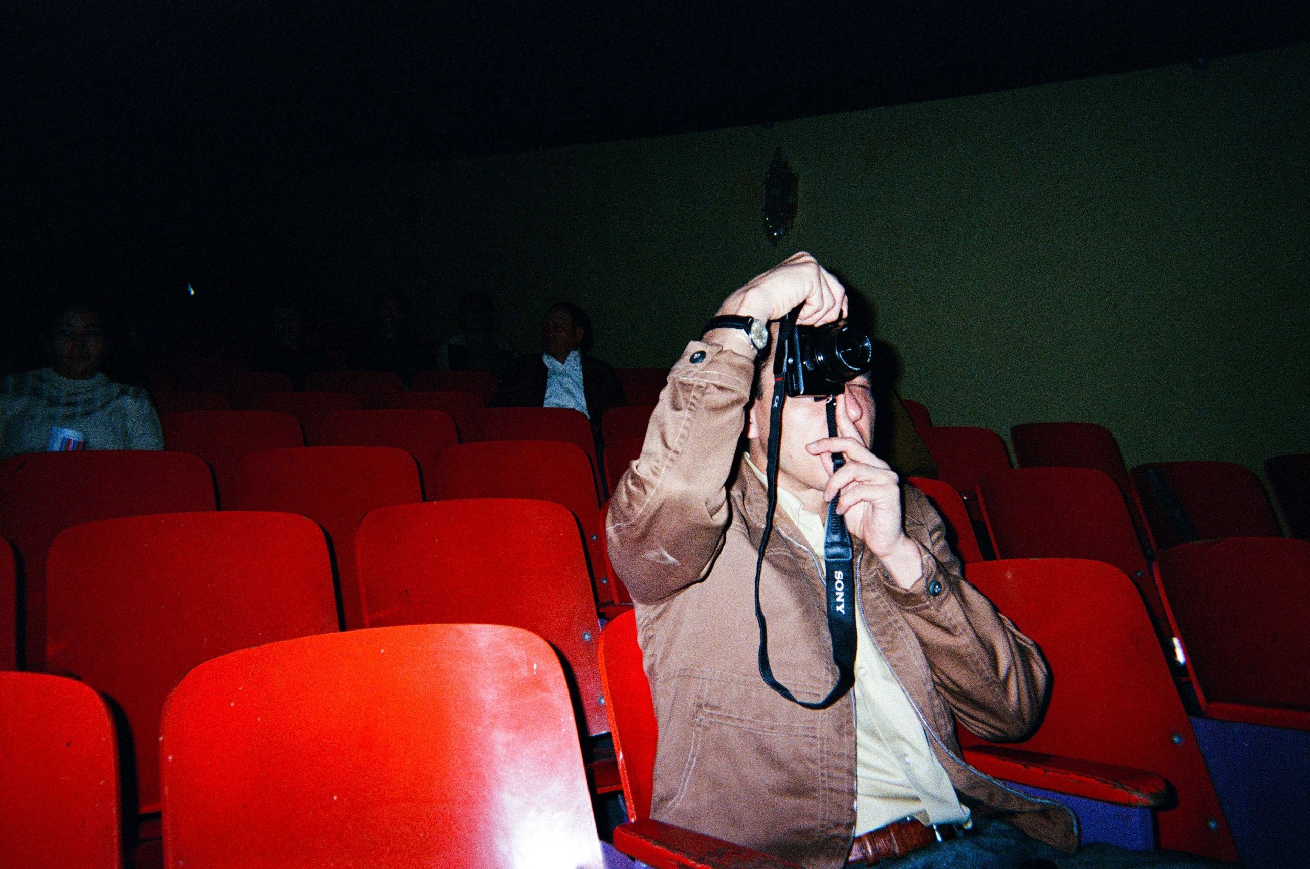 Persona toma foto en cine con asientos rojos.