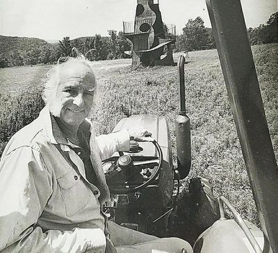 Griffis Sculpture Park founder Larry Griffis Jr. driving a tractor in a field with a sculpture in th