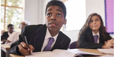 Black boy looking up at teacher during class work
