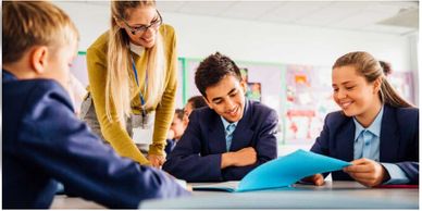 students in classroom looking at a workbook with teacher