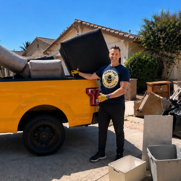 Man loading furniture into a yellow pickup truck in a residential driveway.