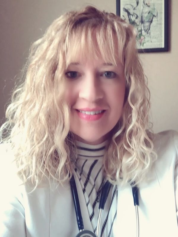 Smiling female doctor with curly blonde hair and stethoscope.