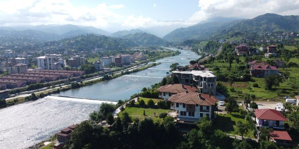 A scenic river flowing through a town with surrounding hills and buildings.