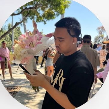 Man holding flowers and phone outdoors.