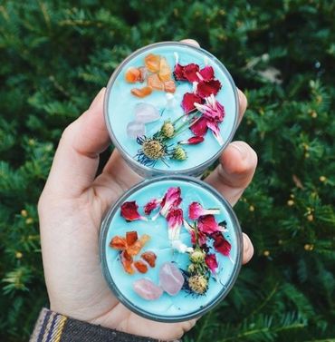Two light blue soy wax candles with rose quartz crystals and pink flowers 
