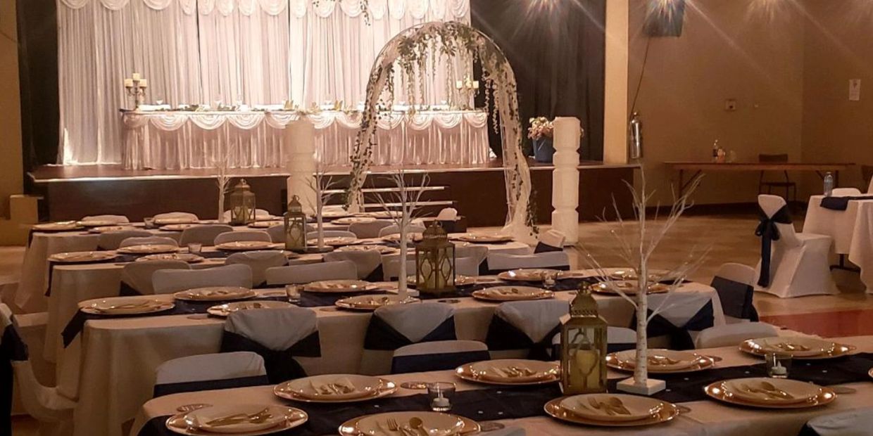 Elegant banquet hall with decorated tables and a floral arch.