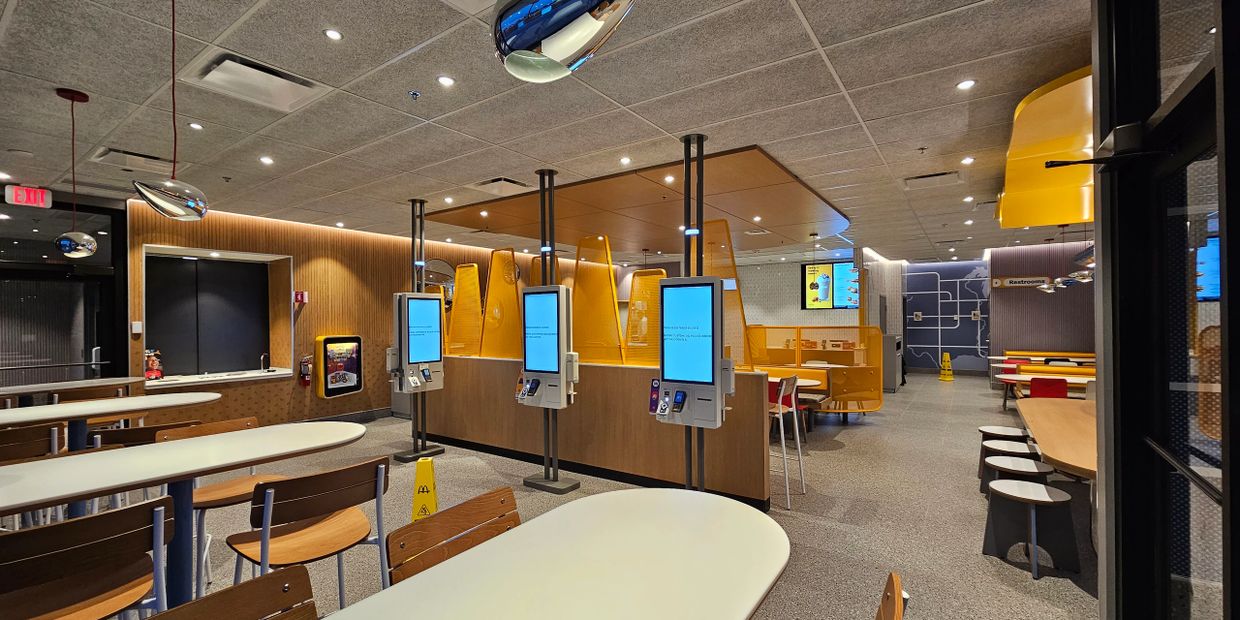 Modern fast-food restaurant interior with self-order kiosks and seating areas.