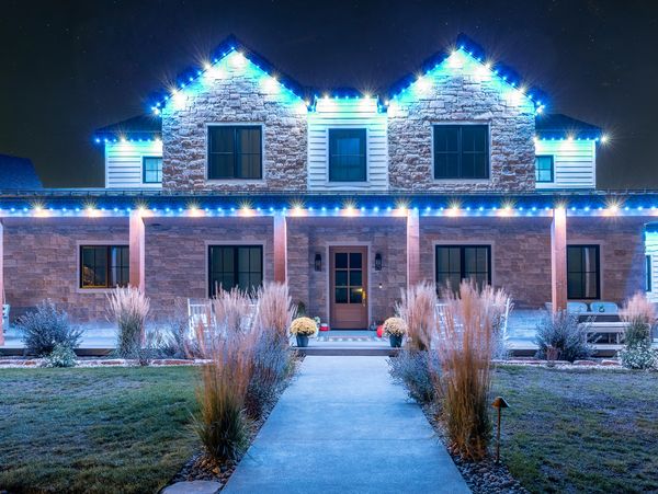 Stone house decorated with blue Christmas lights at night.