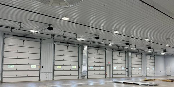 Empty industrial warehouse with multiple garage doors and polished concrete floor.