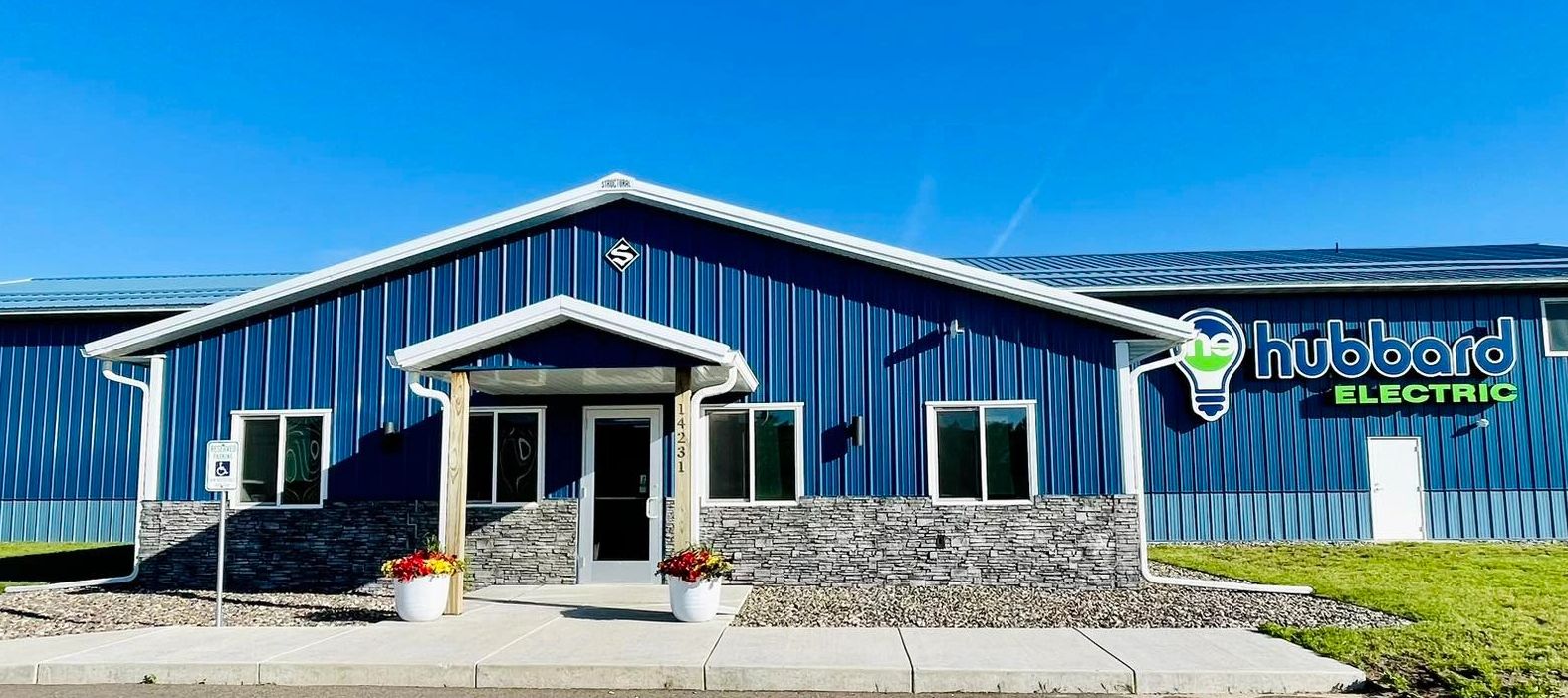 Blue commercial building with "Hubbard Electric" sign and clear sky.