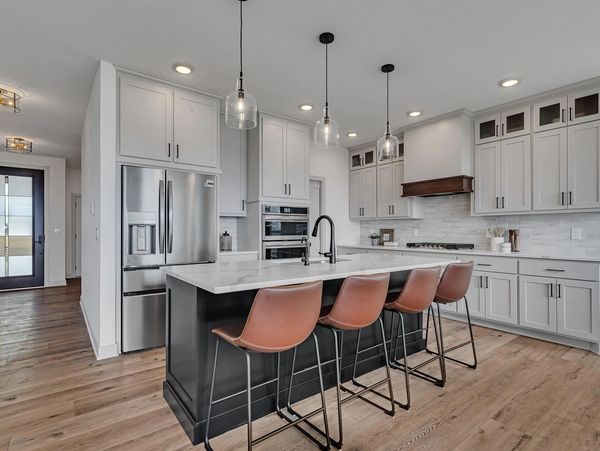 Modern kitchen with island and four leather bar stools.