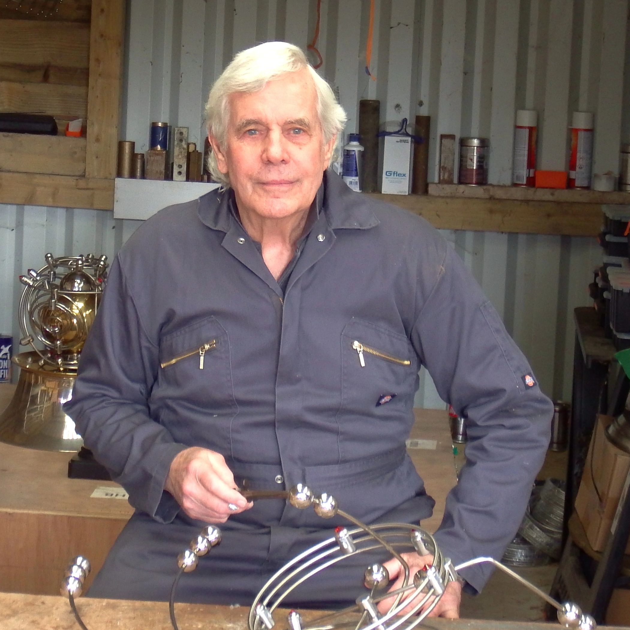 Elderly man in workshop holding a kinetic sculpture.