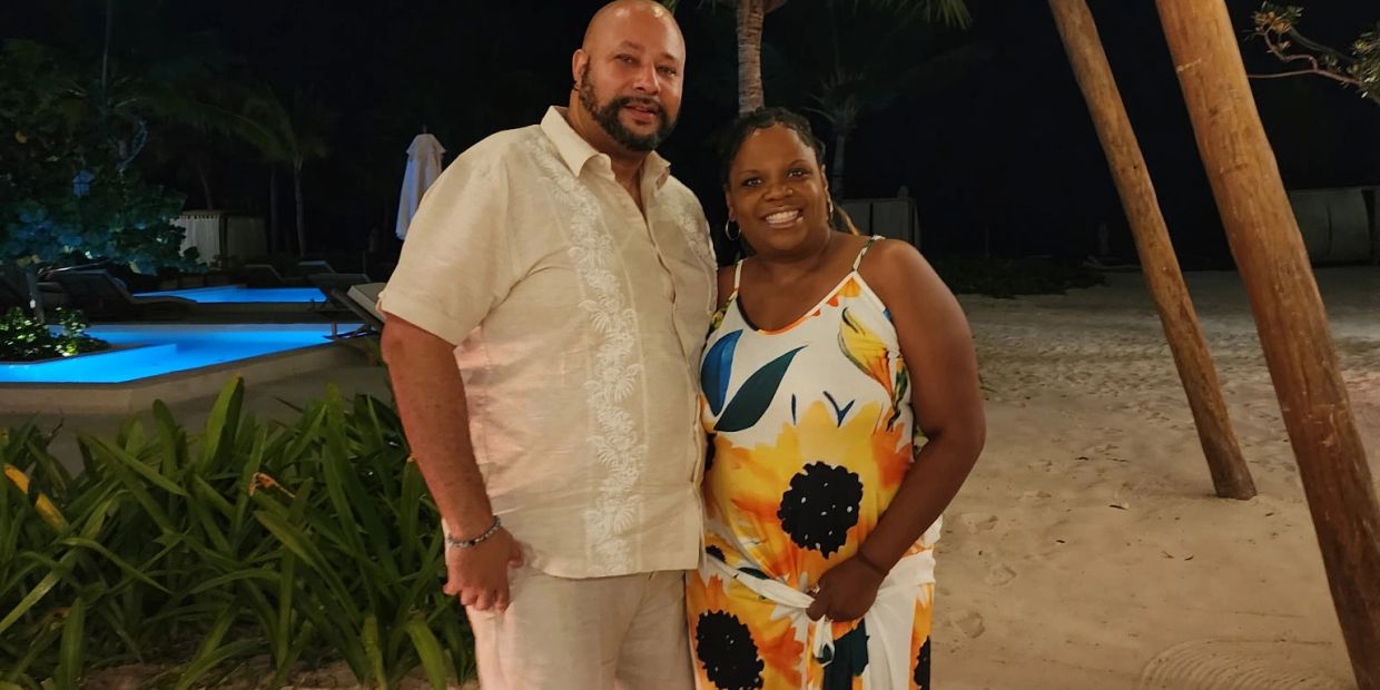 Couple standing on beach at night, smiling.