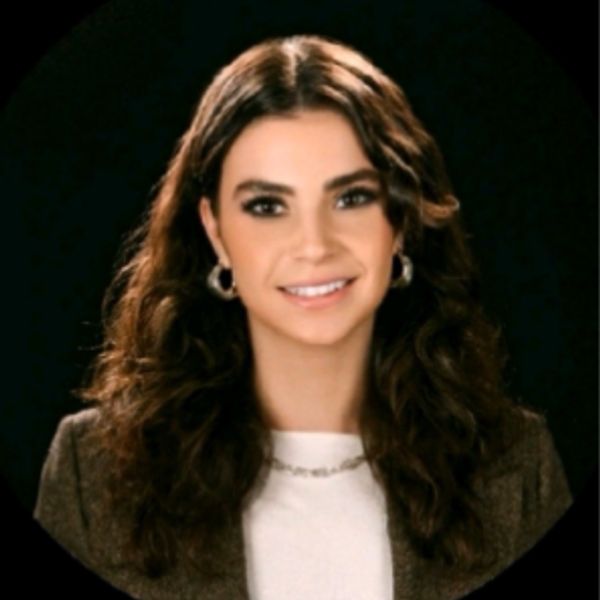 Young woman with curly hair smiling against a dark background.