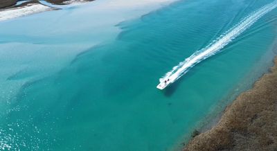 Aerial view of a boat riding through a waterway near Wrightsville Beach with clear water.