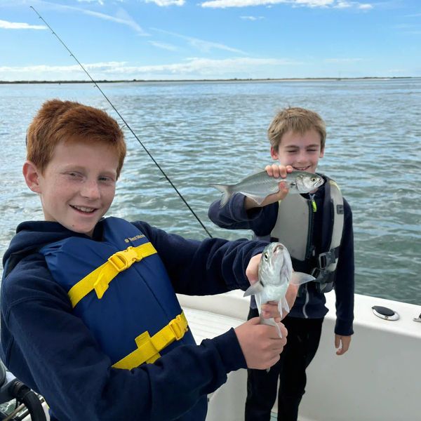 Two boys each hold bluefish they caught while on a fishing charter at Wrightsville Beach, NC.