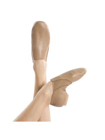 Tan leather jazz shoes worn on crossed legs against white background.