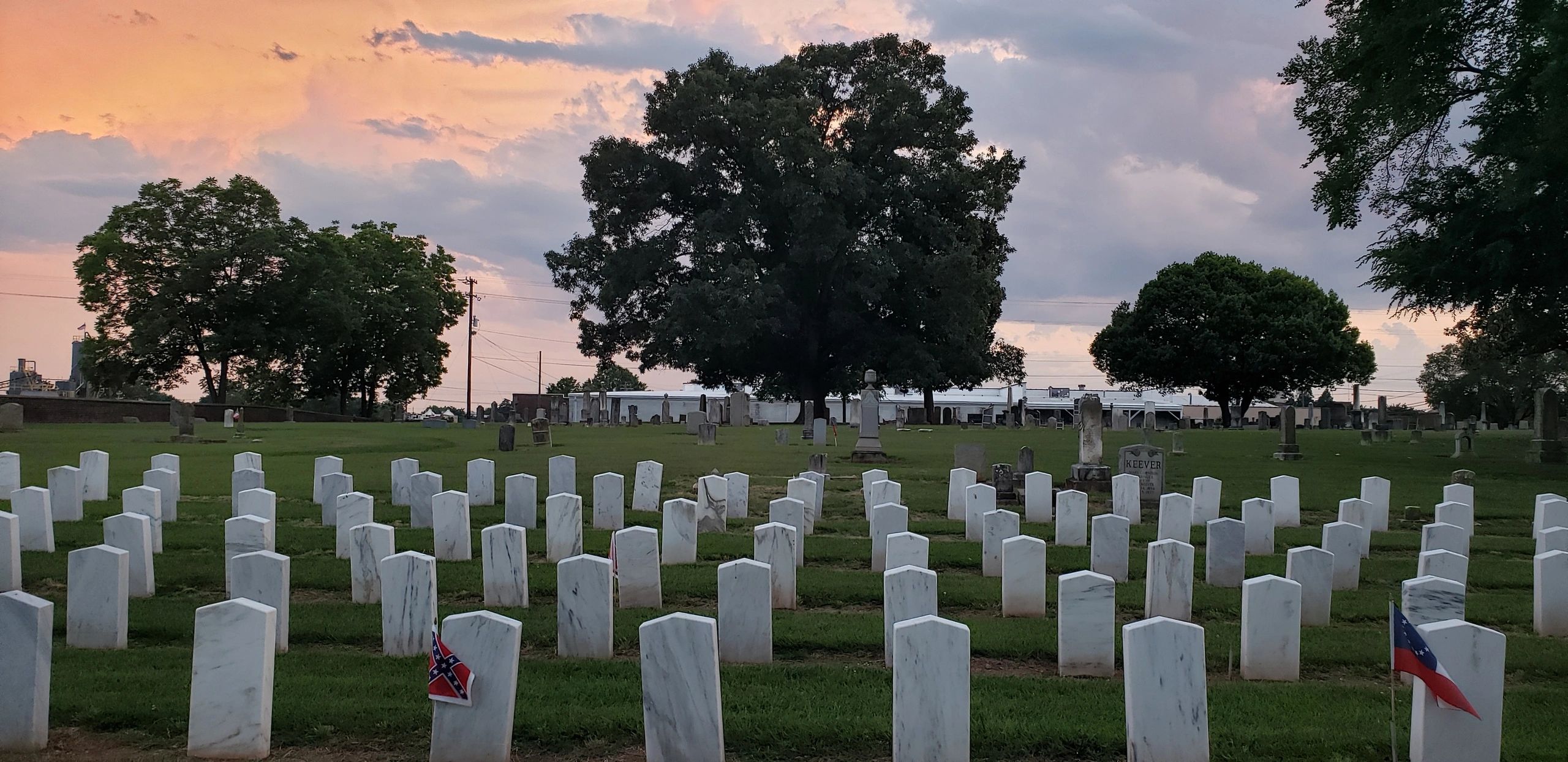 Cemetery at sunset with American and Confederate flags on graves.