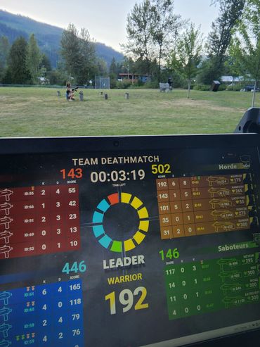 Outdoor gaming setup with a scoreboard displayed on a screen against a park backdrop.
