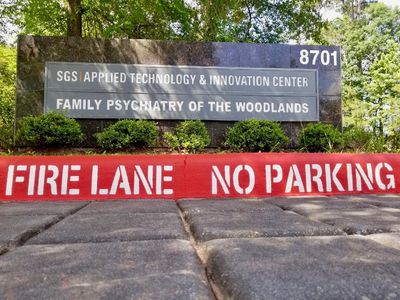 Sign for Family Psychiatry of The Woodlands with fire lane no parking curb.