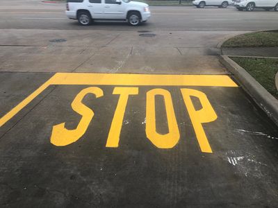 Concrete pavement with a yellow STOP sign painted.