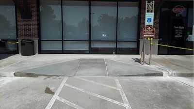 Empty wheelchair-accessible parking spot outside a building.