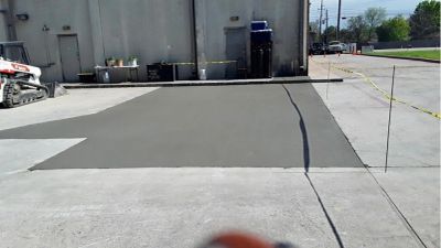 Freshly poured concrete patch outside a building.