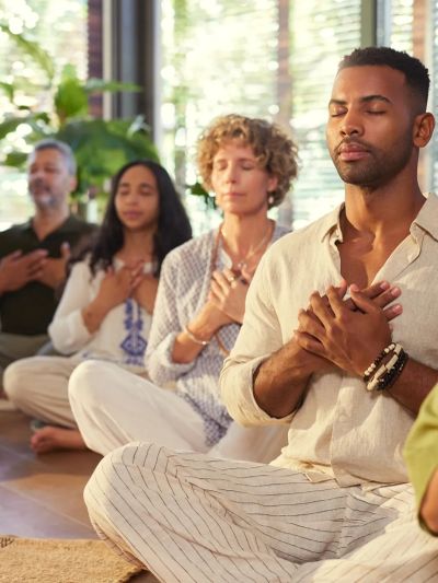 Group meditation session with peaceful expressions and hands on chest.