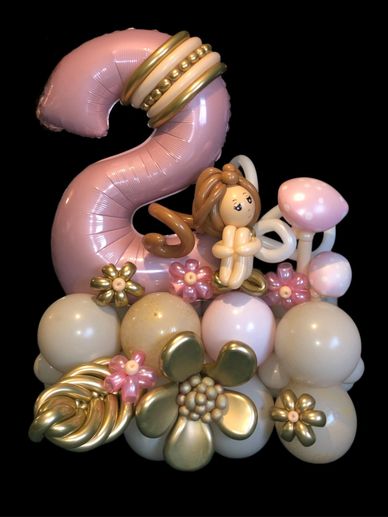 Large pink number 2 balloon arranged with balloon fairy and flowers to create a display 