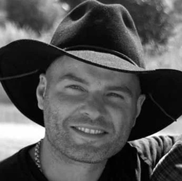 Man smiling wearing a cowboy hat.