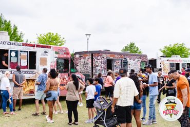 People enjoying a food truck festival on a cloudy day.