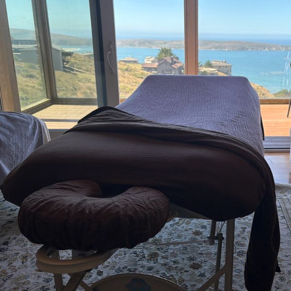 Massage table by large windows with ocean view.