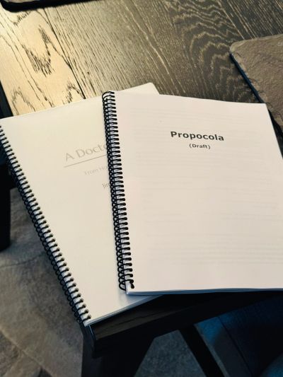 Two spiral-bound drafts on a wooden table.