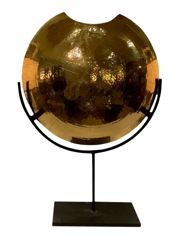 Decorative hammered brass bowl on black metal stand.