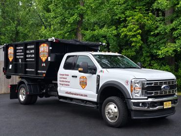 A white and black truck parked on asphalt with greenery in the background.