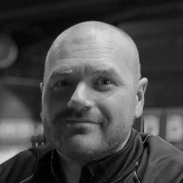 Portrait of a smiling bald man in black and white.