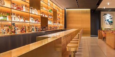 Sleek modern bar with illuminated shelves and wooden stools.