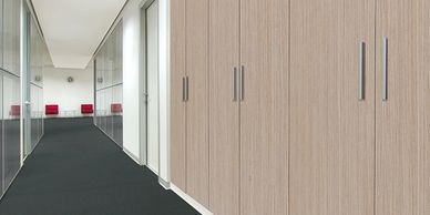 Modern office hallway with wooden cabinets and glass walls.