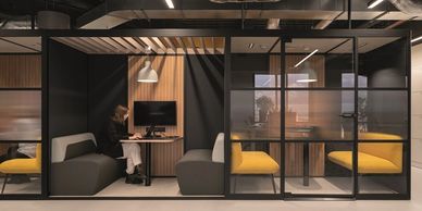 Modern office pods with seating and workspace separated by glass walls.