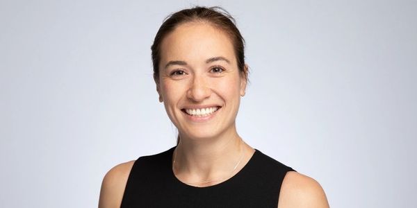 Woman smiling wearing a black sleeveless top.