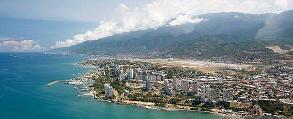 Coastal city with mountains and clouds in the background.