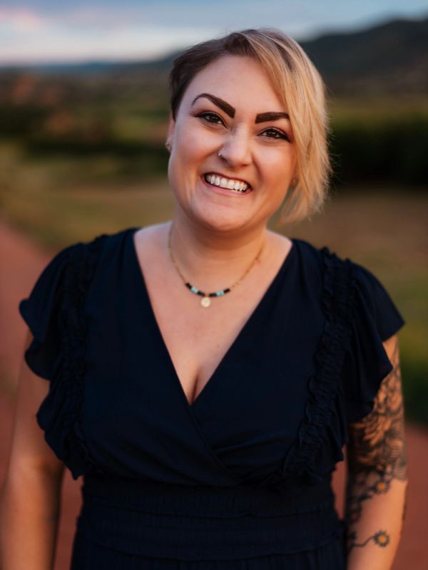 Smiling woman in dark dress outdoors.