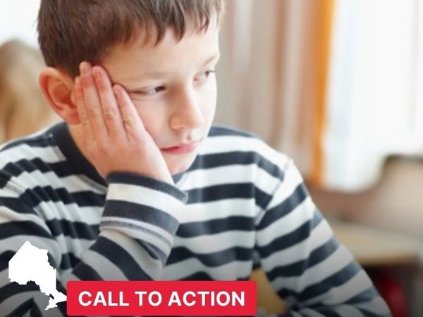 A boy in a striped shirt looks thoughtful and concerned indoors.